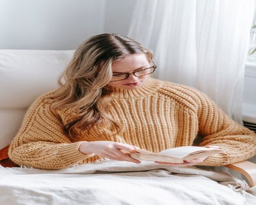 A person relaxing reading a book in a comfortable armchair during the weekend