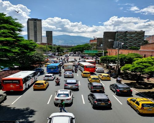 A view from a window showing busy urban traffic and public transportation in Colombia